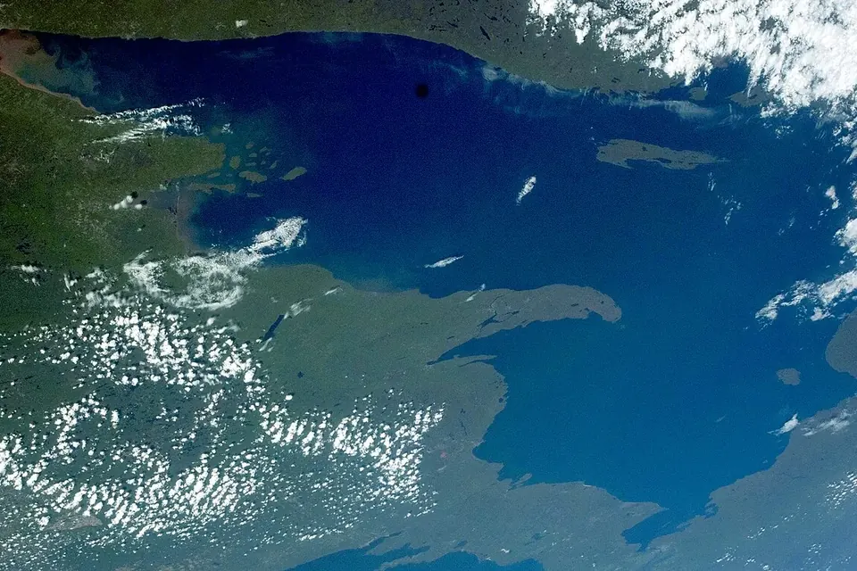 Satellite view of a vast deep-blue lake with scattered white clouds over its shores